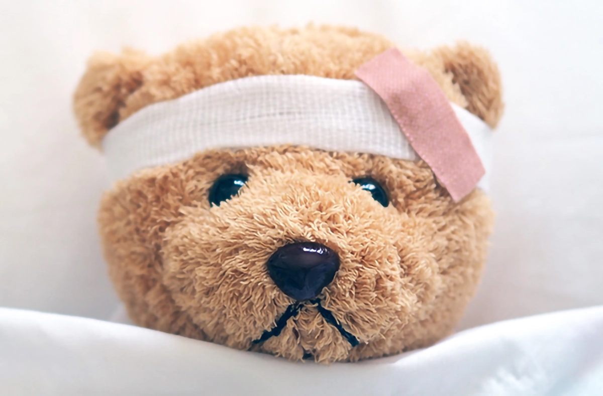 Image of a teddy in bed with bandages